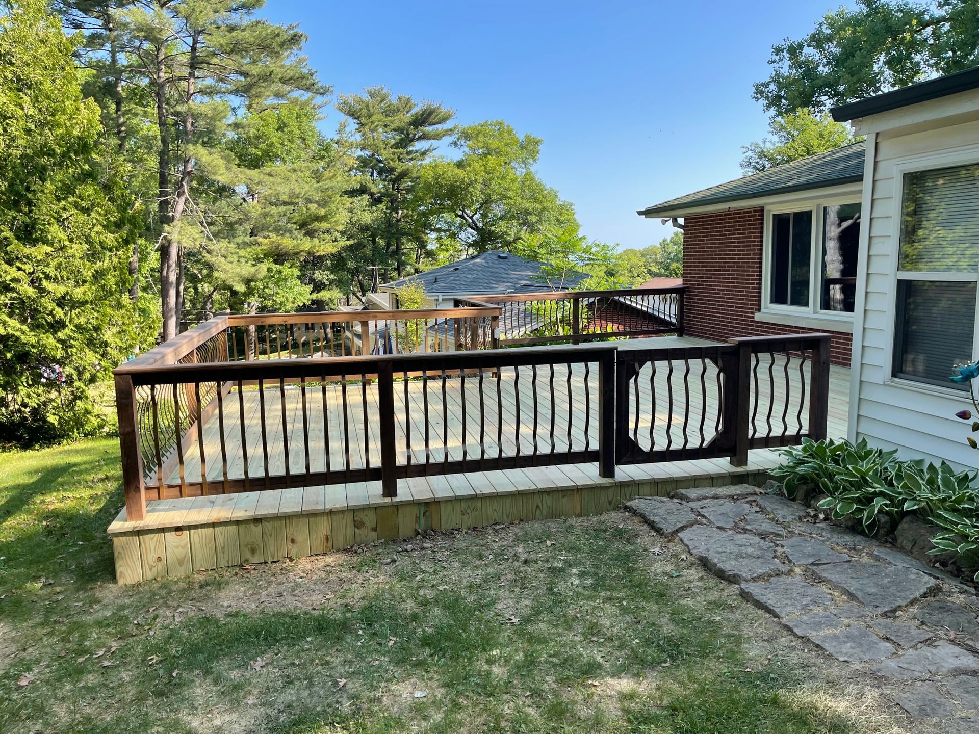 A wooden deck with a railing is in front of a house.