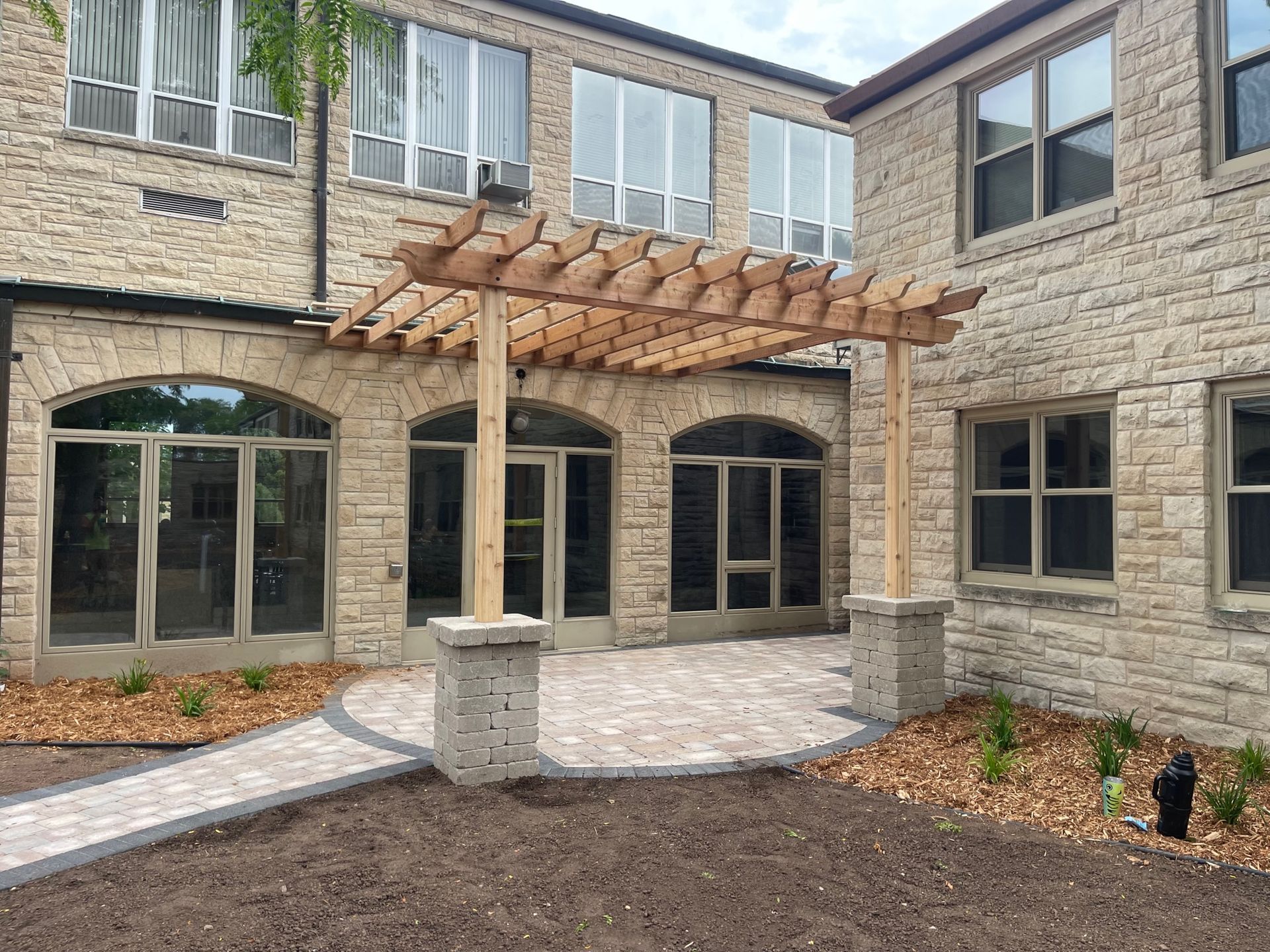 A large brick building with a wooden pergola in front of it