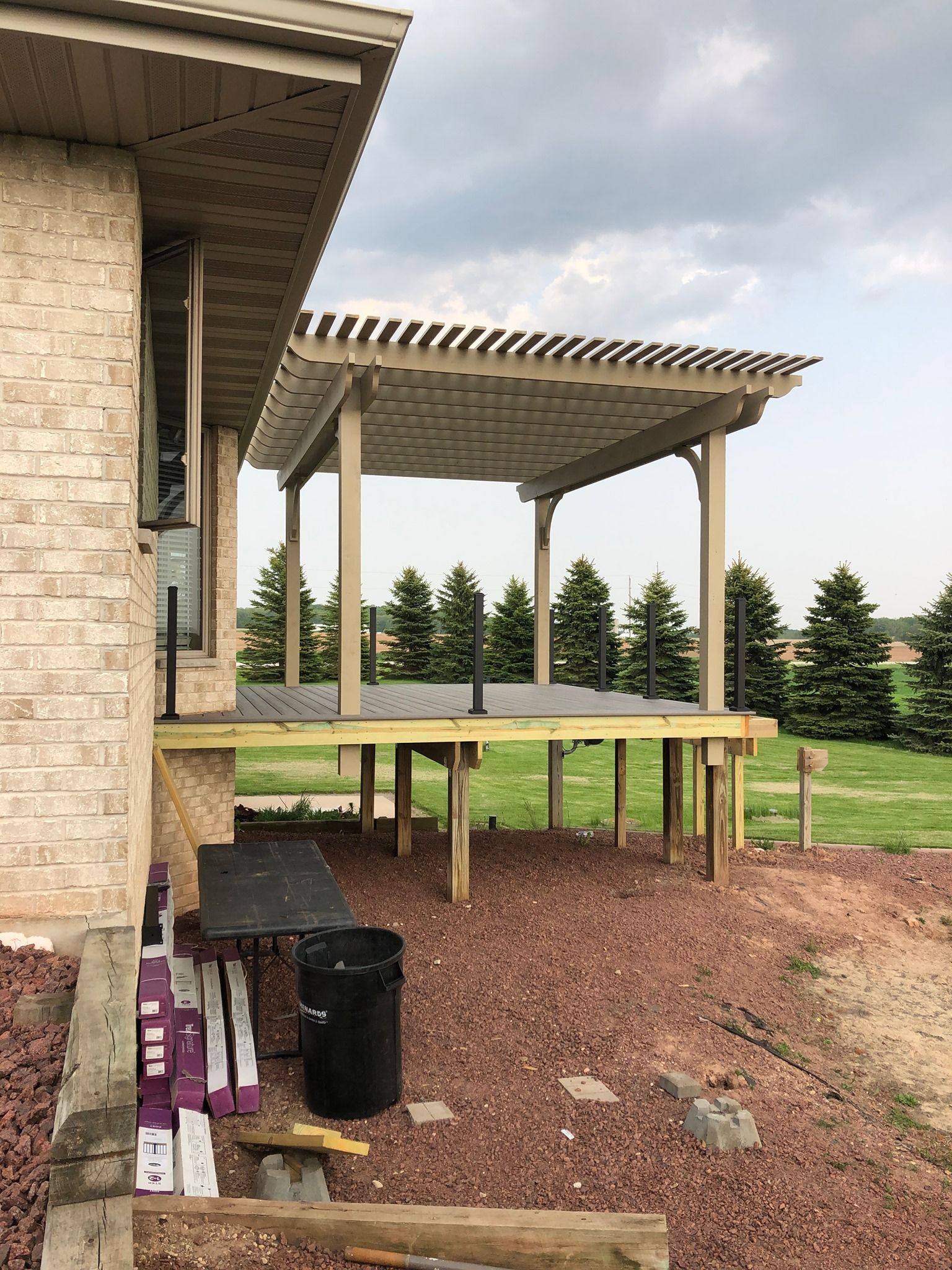A wooden deck is being built next to a brick house.