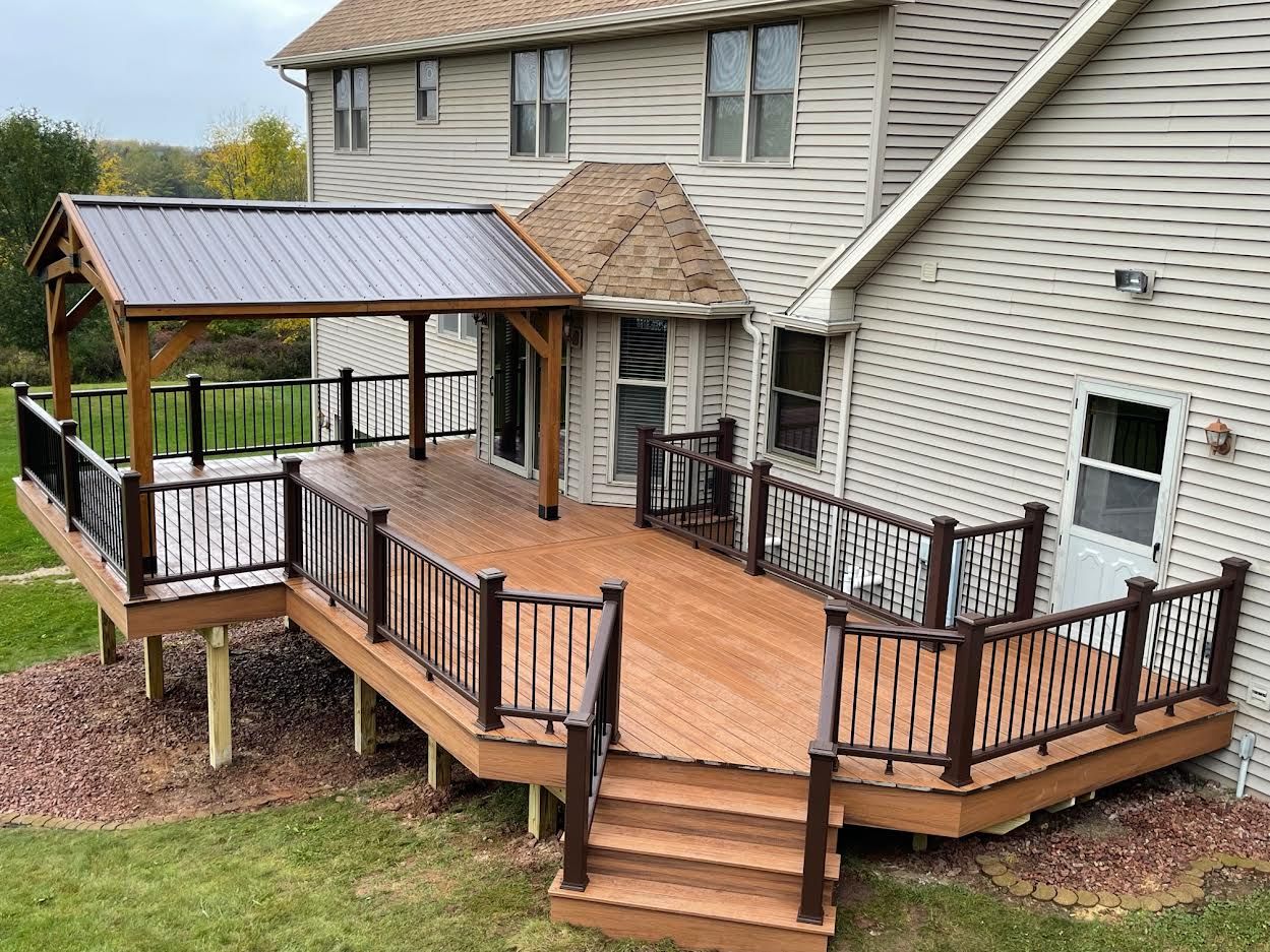 A large wooden deck with a gazebo attached to it is in front of a house.