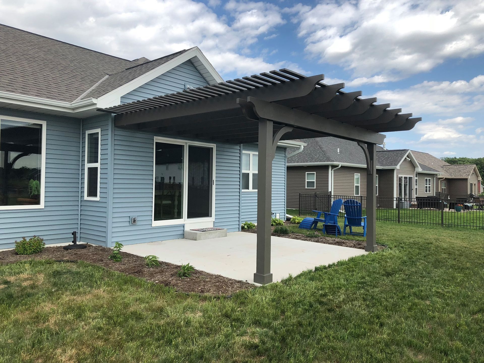 A blue house with a pergola in the backyard.