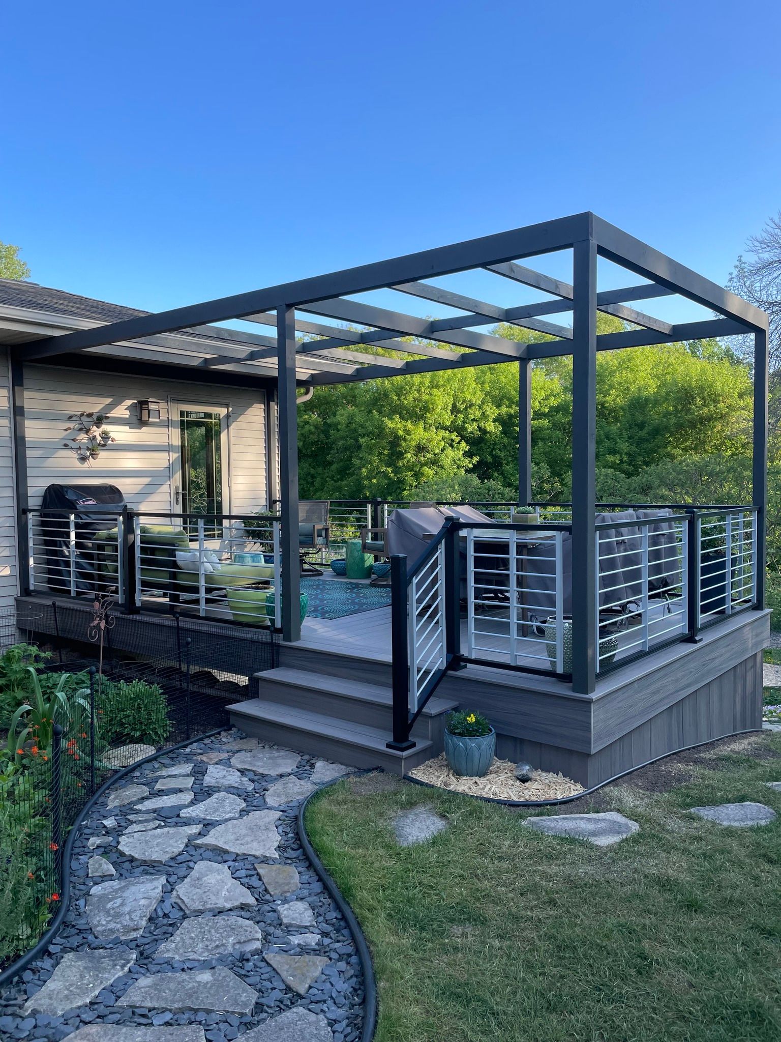 There is a pergola on the deck of a house.