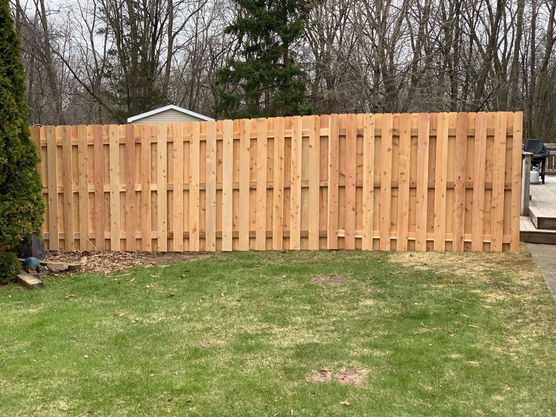 A wooden fence is sitting in the middle of a lush green yard.