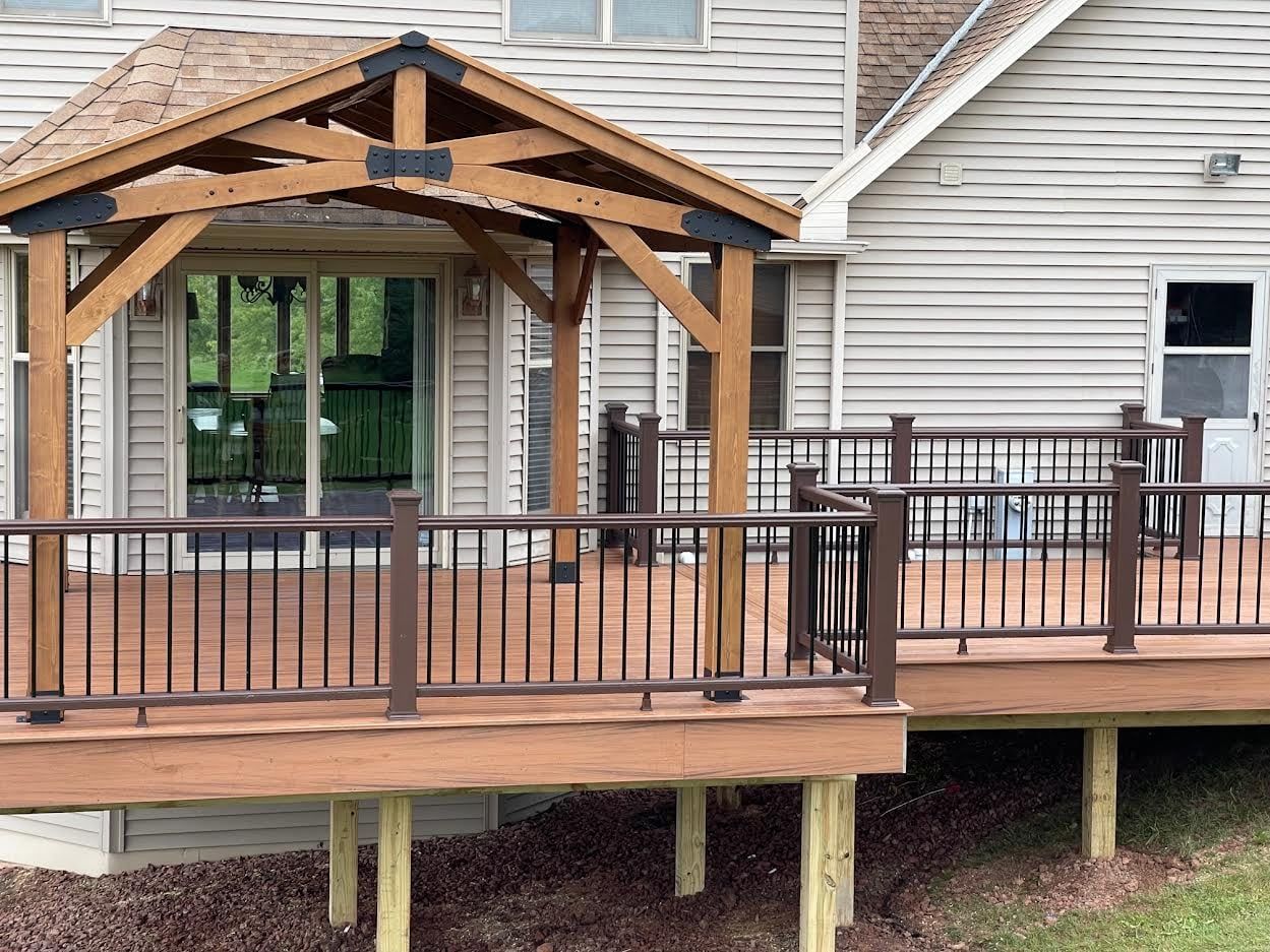 A large wooden deck with a pergola on top of it in front of a house.