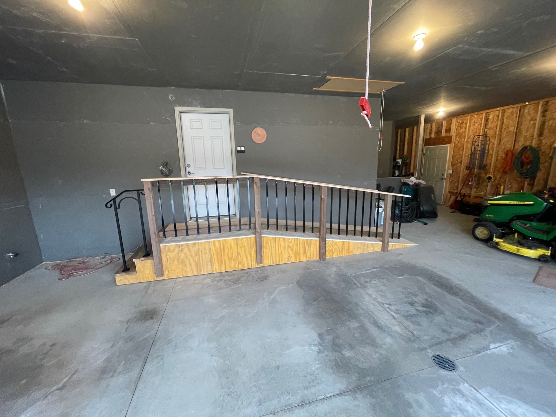 A garage with a ramp and a lawn mower in it.