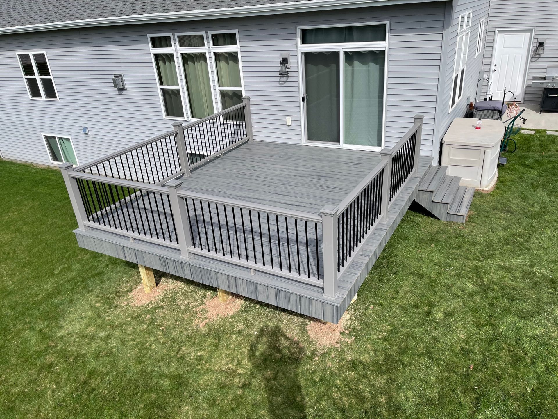 An aerial view of a gray deck in front of a house.