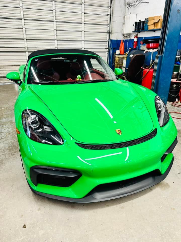 Green Porsche convertible sports car inside a garage.
