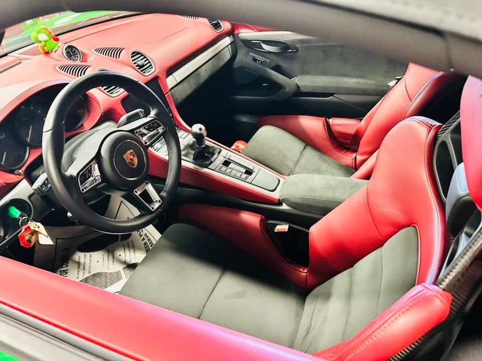 Red and black Porsche interior with steering wheel, seats, and dashboard.
