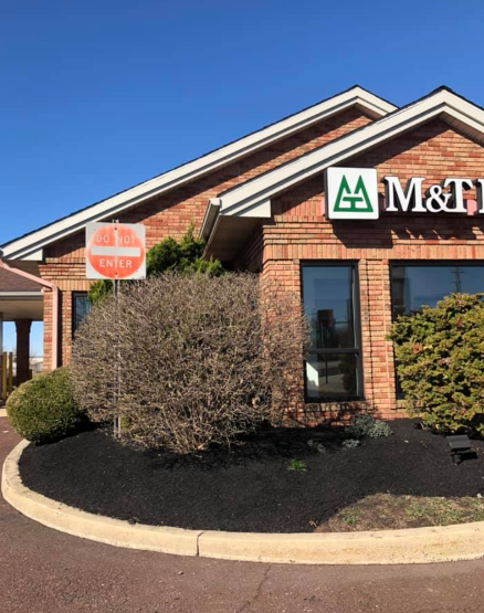 M&T Bank branch exterior with brick siding, landscaping, and a round Do Not Enter sign in front of a blue sky.