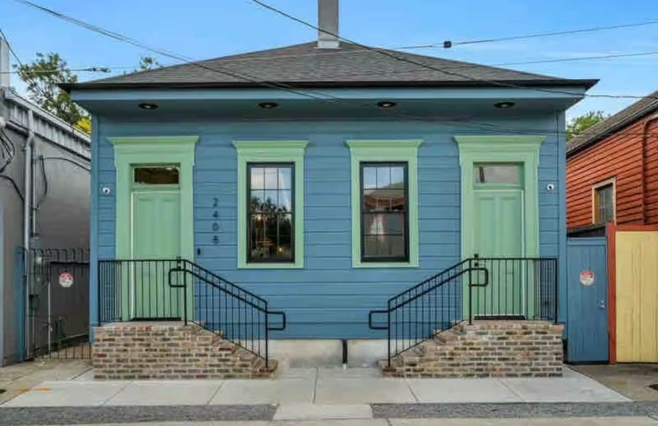 Blue house with green doors and trim; stairs lead to each entry.