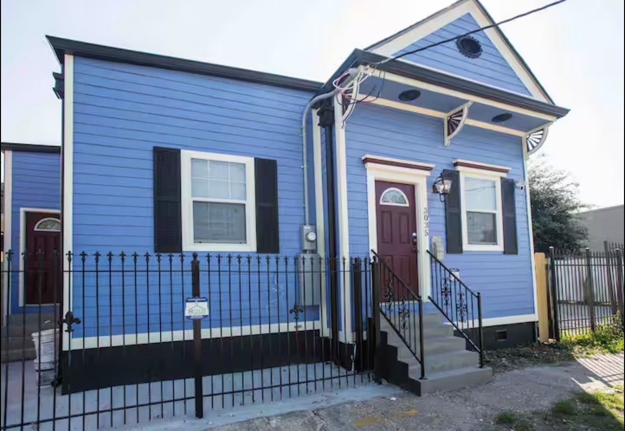 Blue house with dark trim and a black wrought-iron fence.