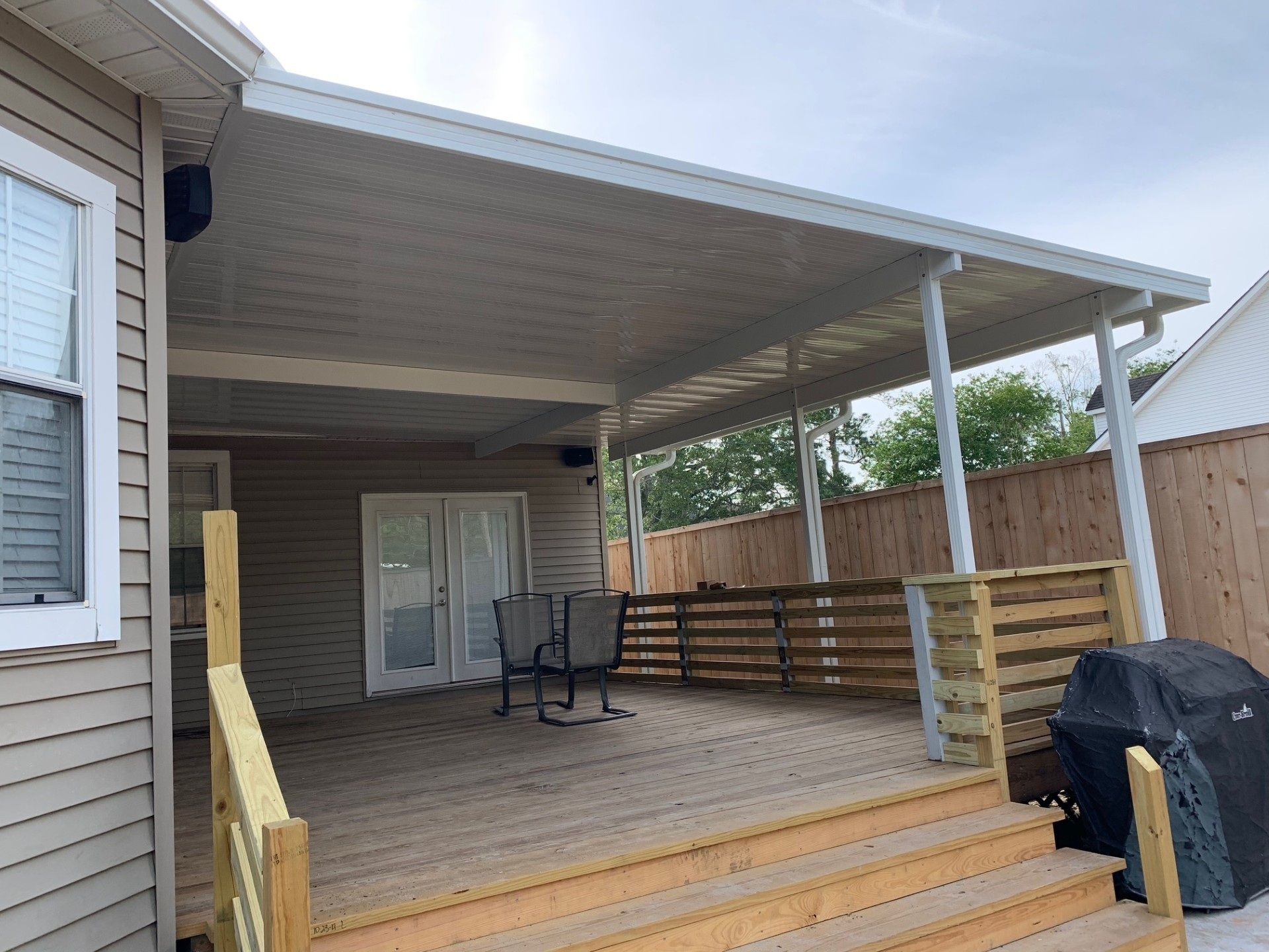 Deck with a covered patio, wooden steps, and a wooden fence.