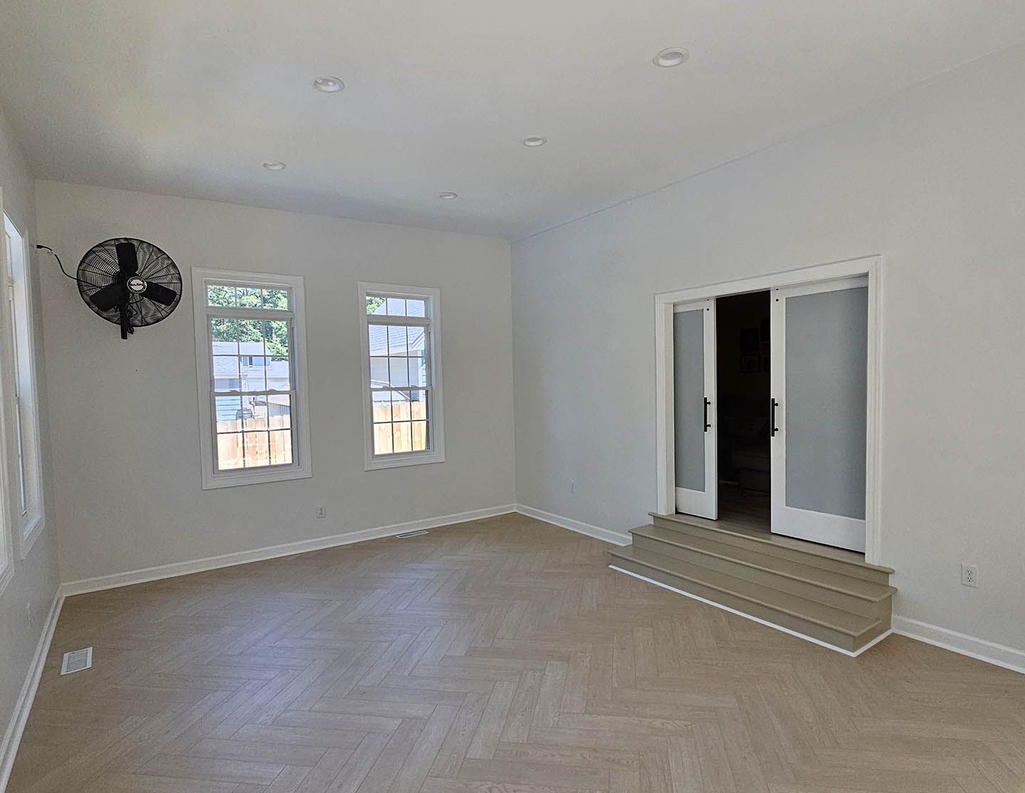 An empty room with a fan on the wall and a sliding glass door.