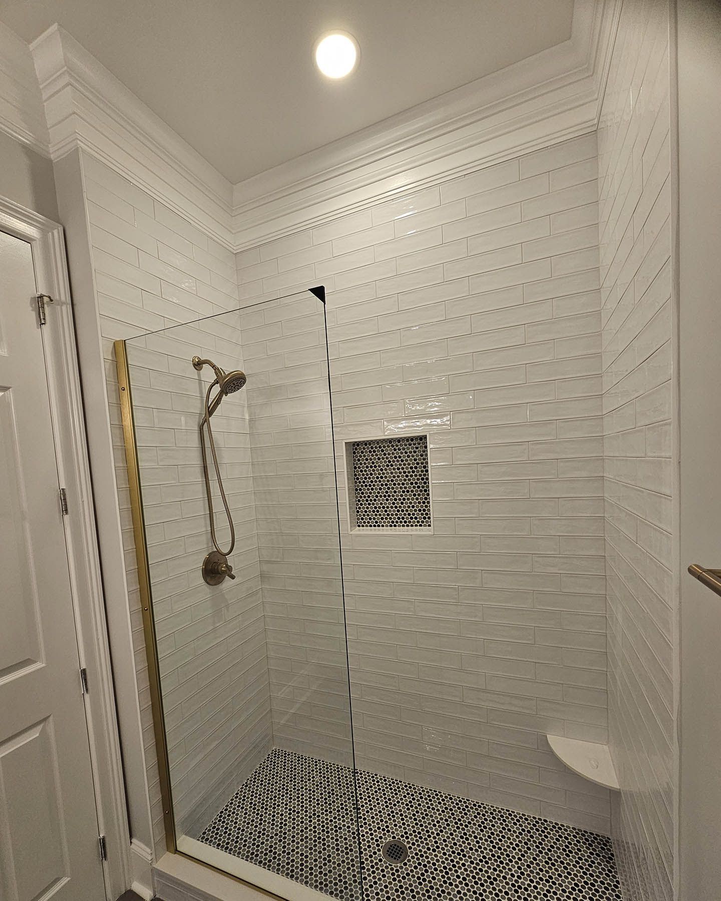 A bathroom with a walk in shower with a glass door.