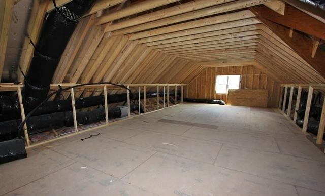 An empty attic with wooden beams and a window.