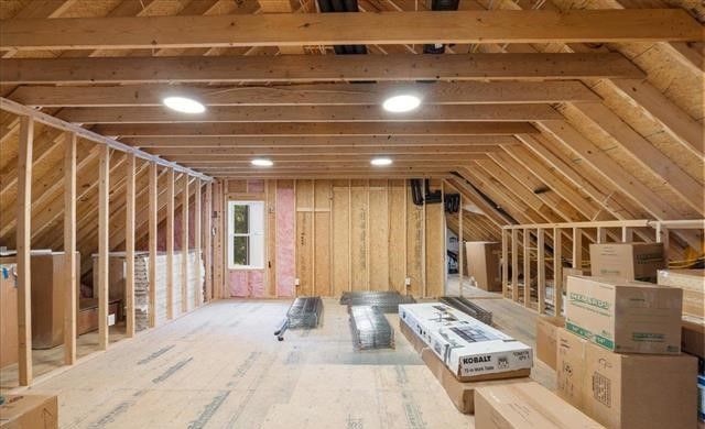 An attic under construction with wooden beams and boxes stacked on the floor.