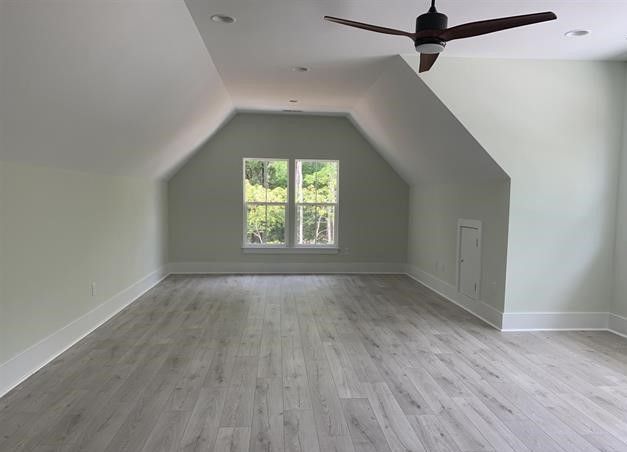 An empty room with a ceiling fan and two windows