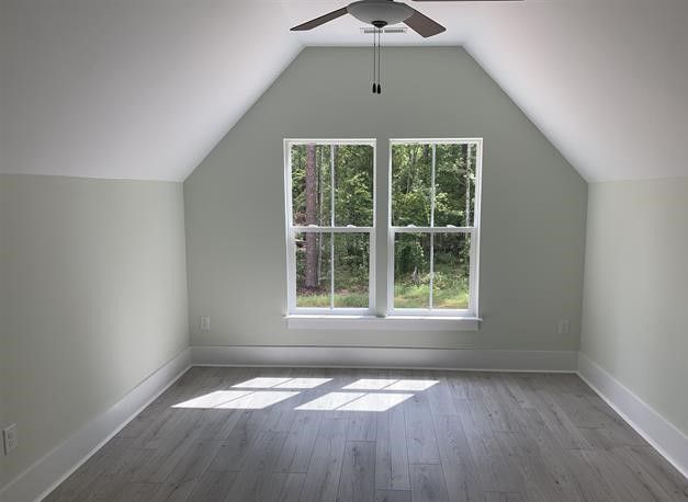 An empty room with a ceiling fan and two windows