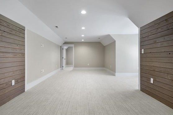 An empty room with white carpet and wooden walls.