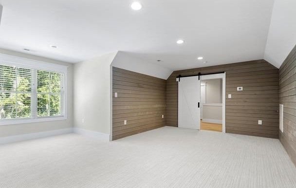 An empty room with a sliding barn door and a large window.