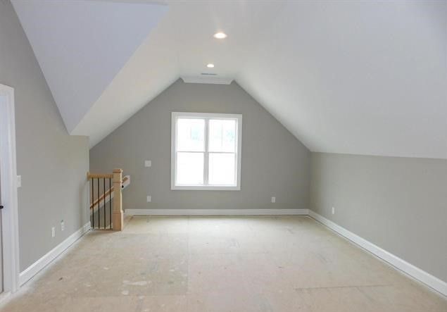 An empty attic with a staircase and a window.