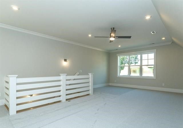An empty room with a white railing and a ceiling fan