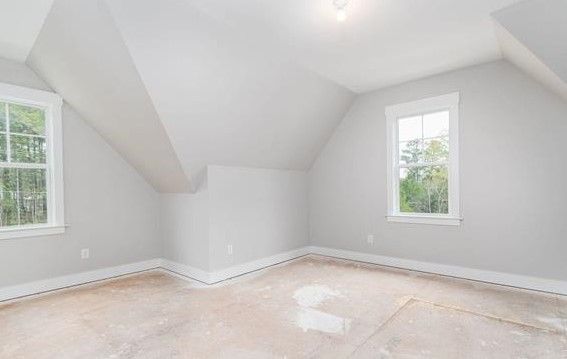 An empty room with a vaulted ceiling and two windows.