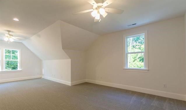 An empty bedroom with a ceiling fan and two windows.
