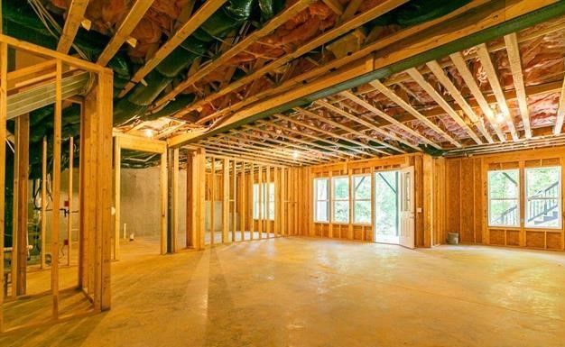 An empty room in a house under construction with wooden beams and insulation.