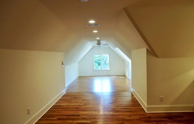 An empty attic with hardwood floors and white walls