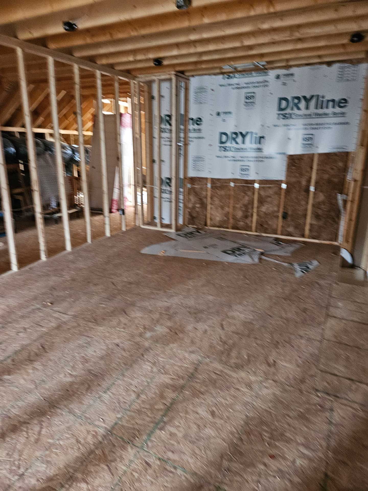A room in a house under construction with dryline on the wall.