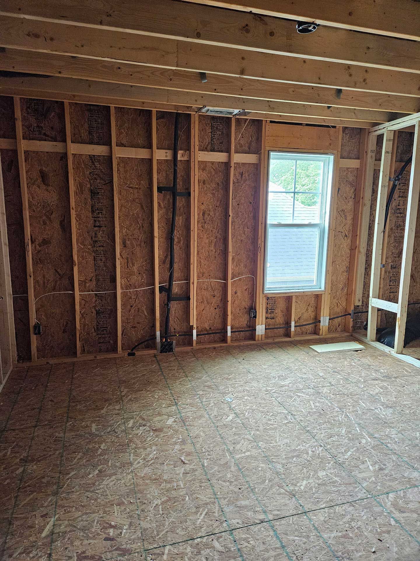 An empty room with wooden beams and a window.