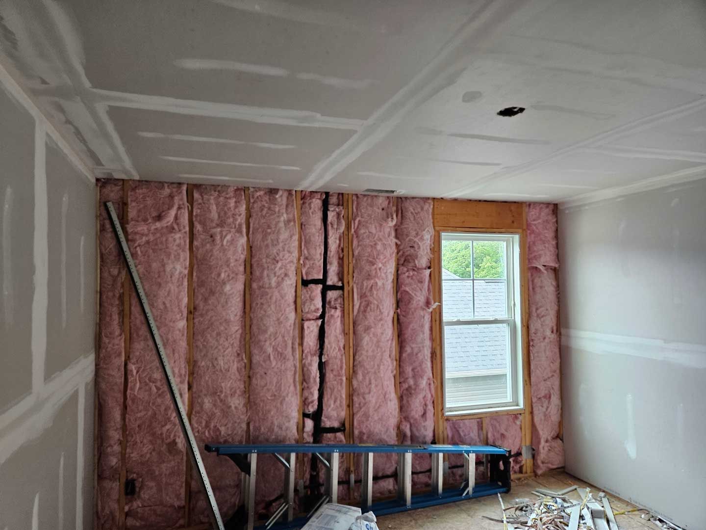 A room with pink insulation on the walls and a window.