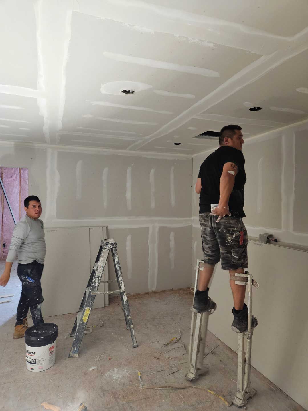 Two men are standing on a ladder in a room