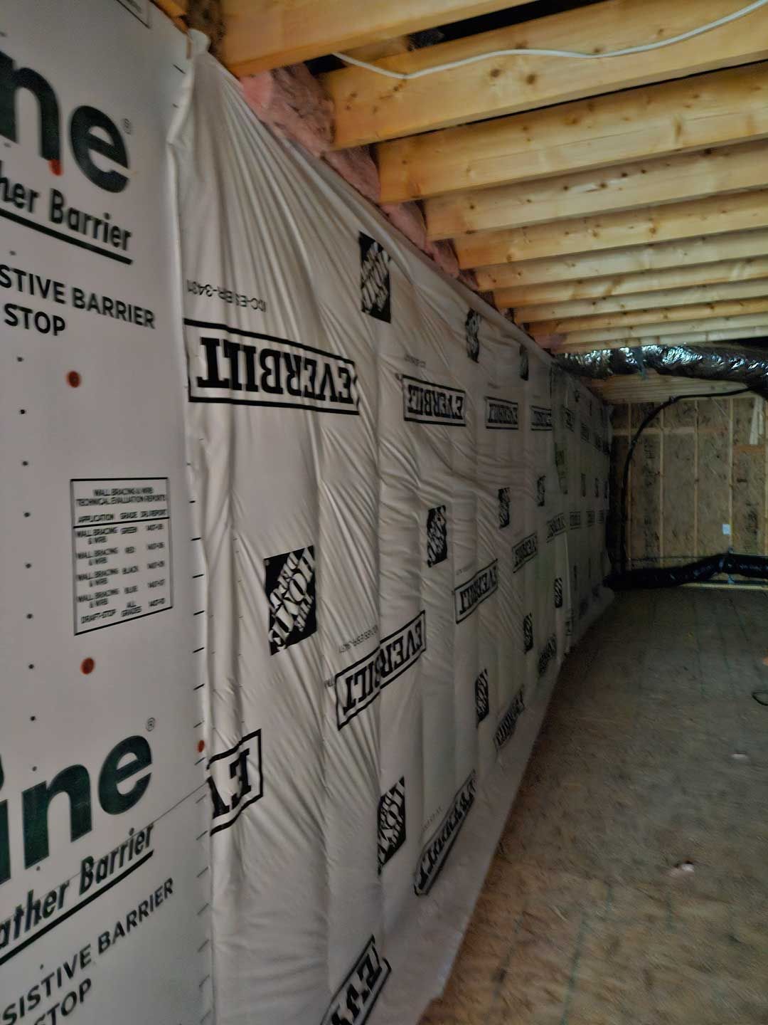 A wall in a basement that is covered in home depot barrier