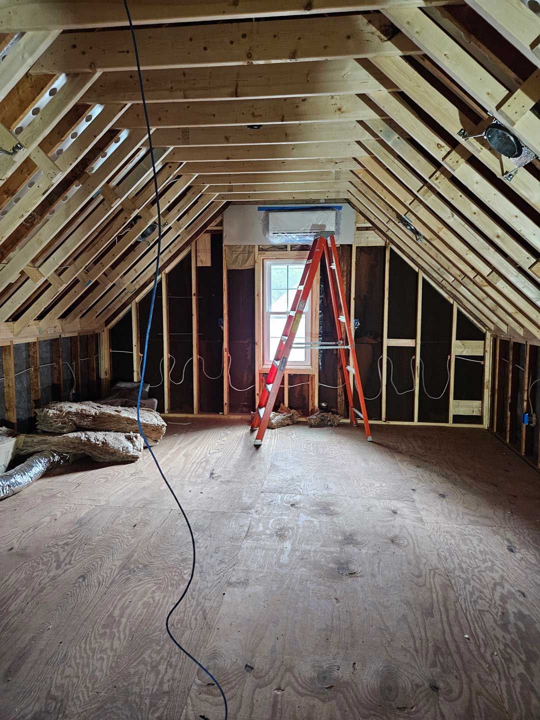 There is a ladder in the attic of a house under construction.