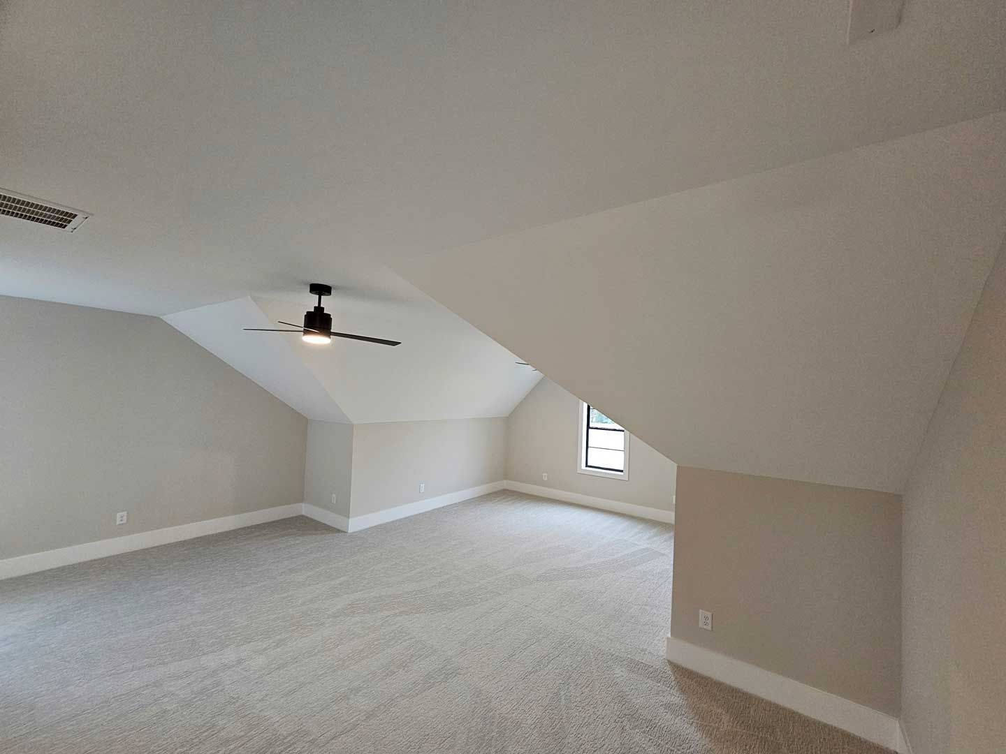 An empty room with a ceiling fan and a window.