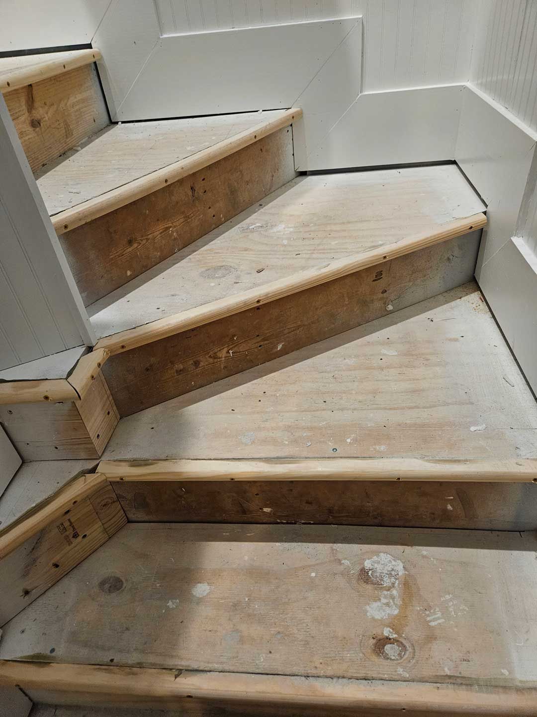 A close up of a wooden staircase with a white railing.