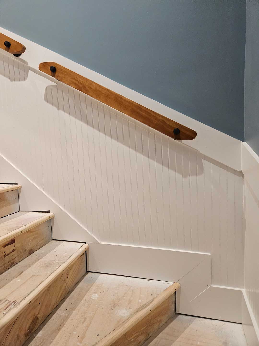 A close up of a wooden staircase with a wooden railing.
