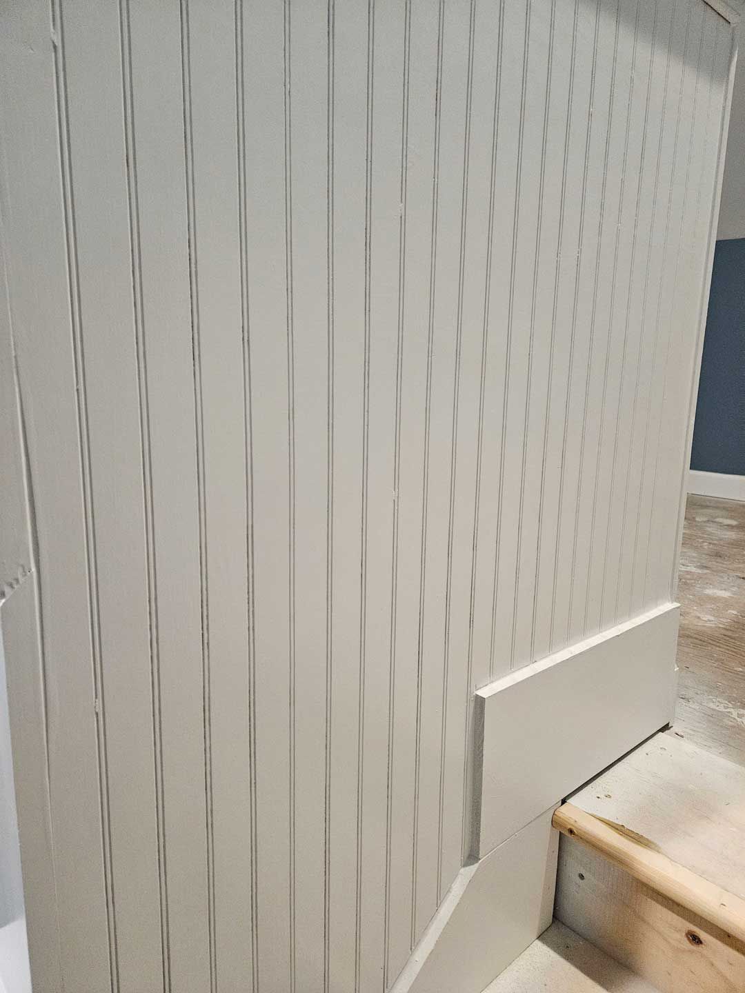 A close up of a white wall with a staircase in the background.