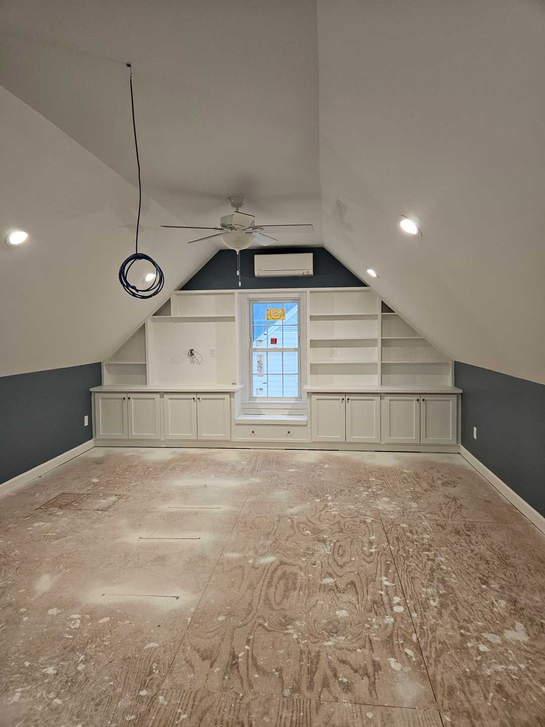 An empty room with a ceiling fan and a window.