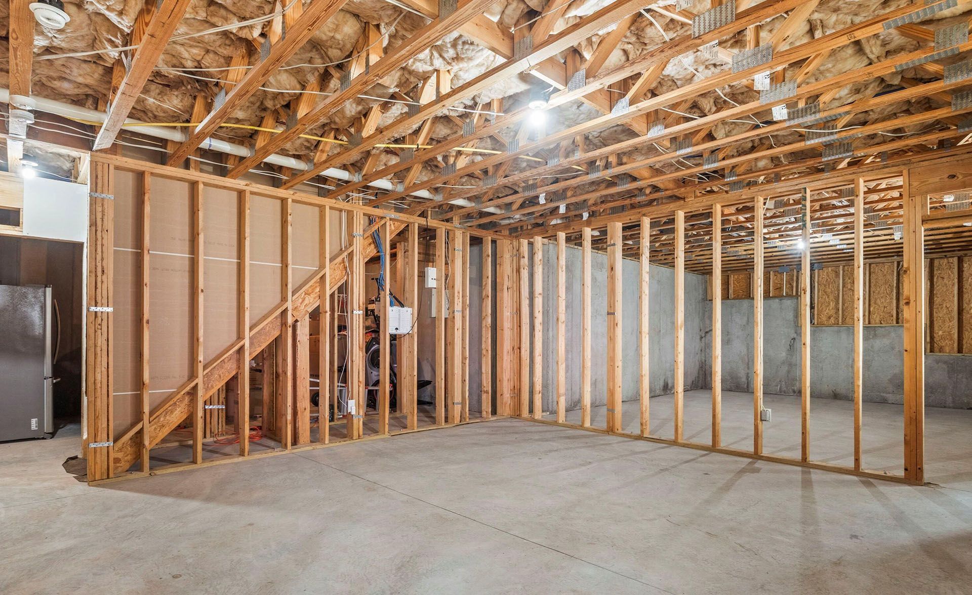 A basement under construction with wooden beams and a staircase.