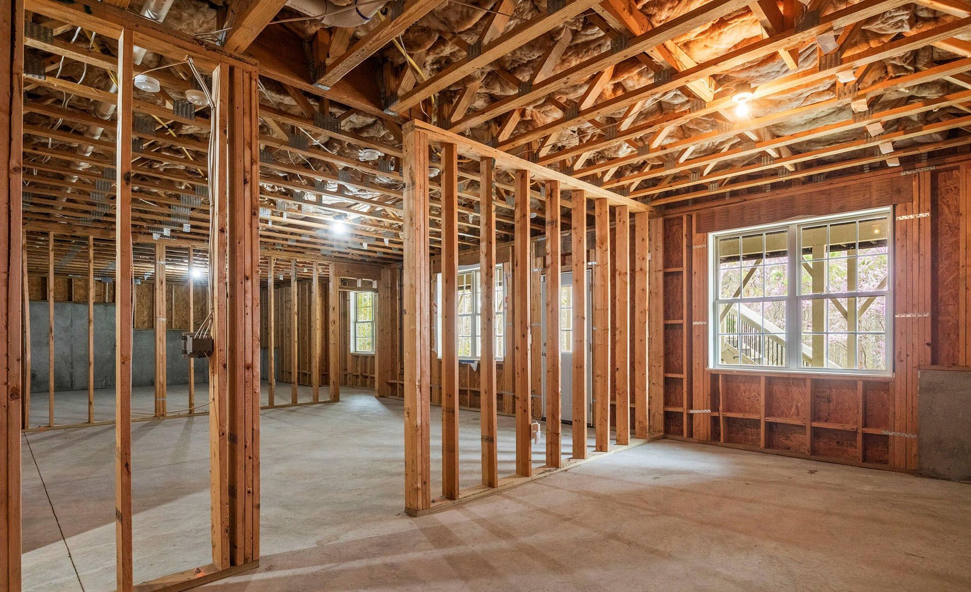A room in a house under construction with wooden beams and windows.