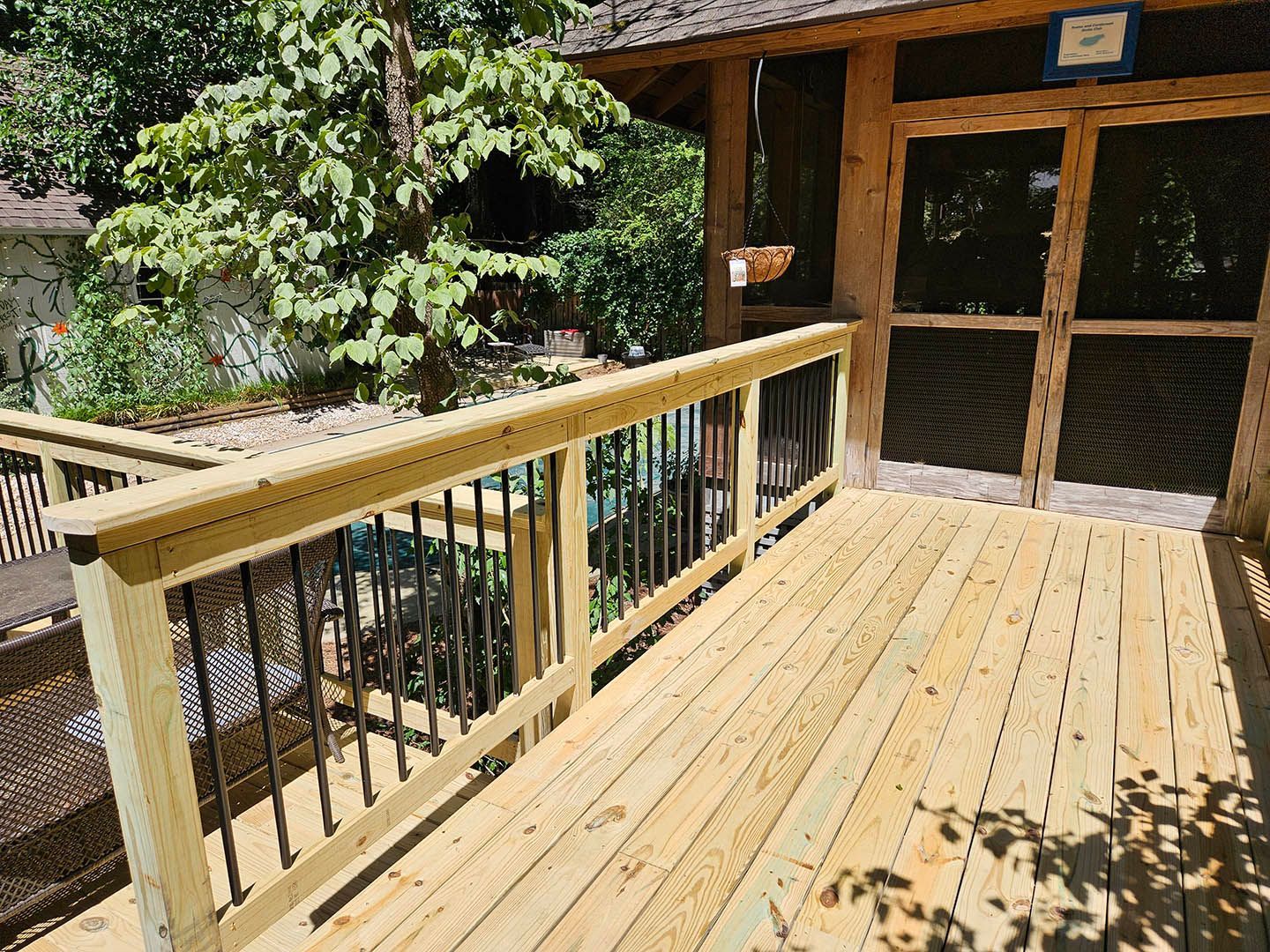 A wooden deck with a screened in porch in the background.
