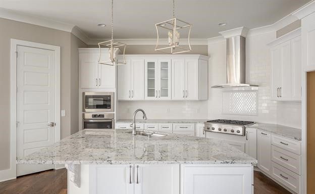 A kitchen with white cabinets and granite counter tops.