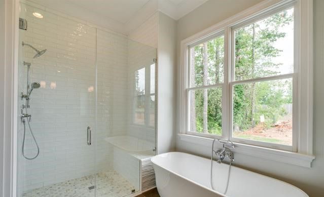 A bathroom with a tub , shower , and window.