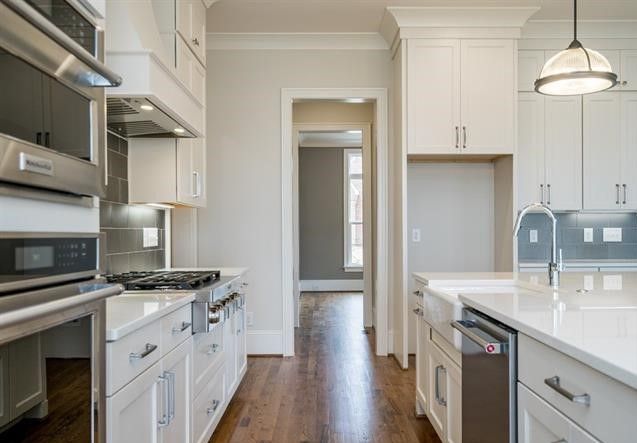 A kitchen with white cabinets , stainless steel appliances , a sink , and a stove.