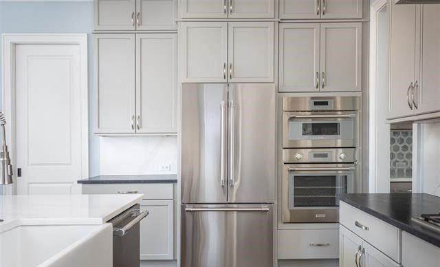 A kitchen with stainless steel appliances and white cabinets.