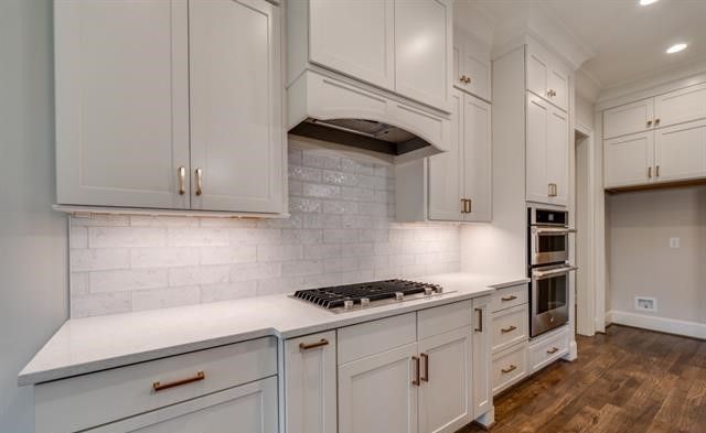 A kitchen with white cabinets , a stove top oven , and a refrigerator.