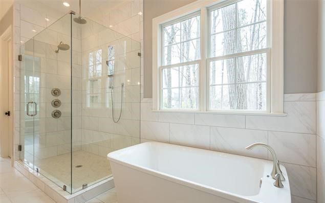 A bathroom with a tub , shower , and window.